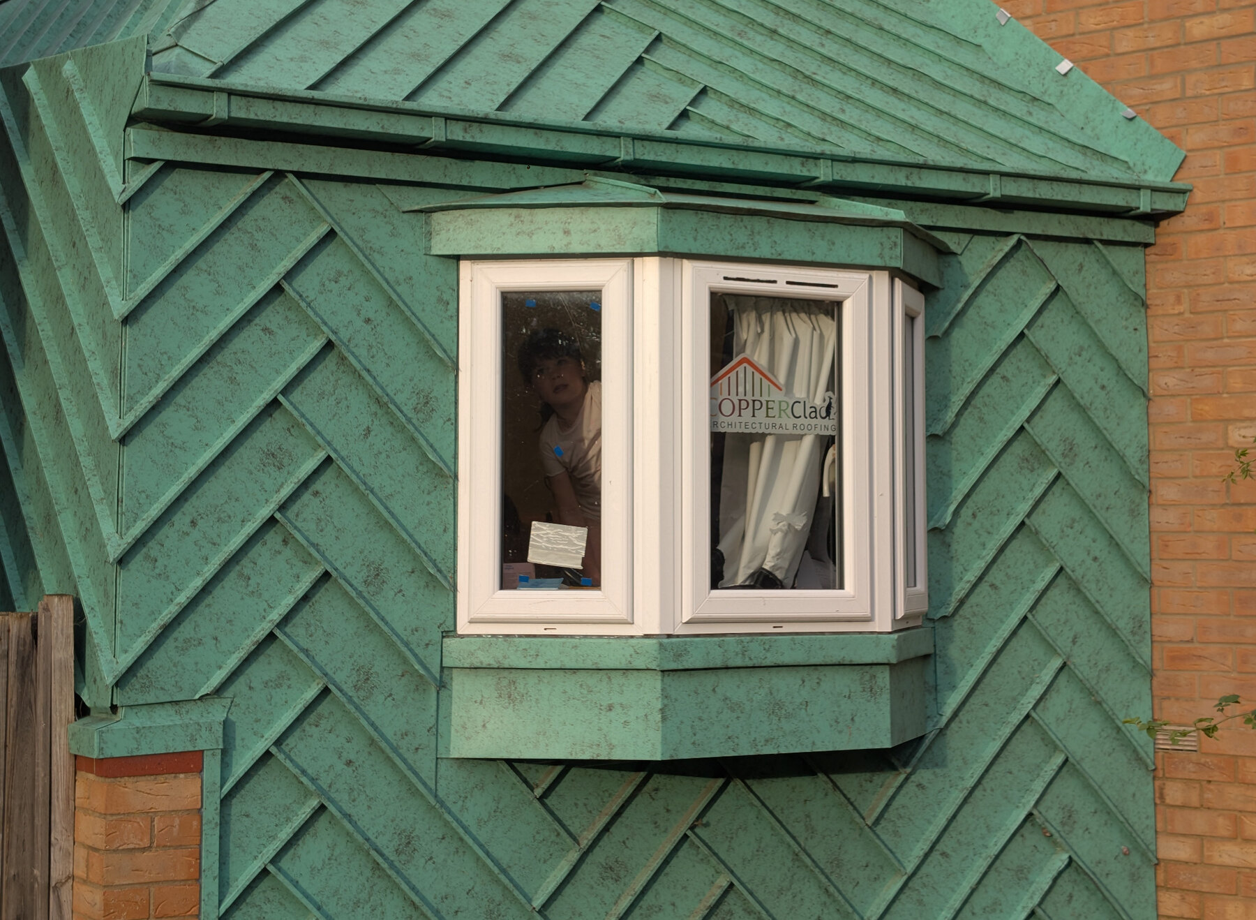 Green metal-clad extension with a standing-seam roof and bay window